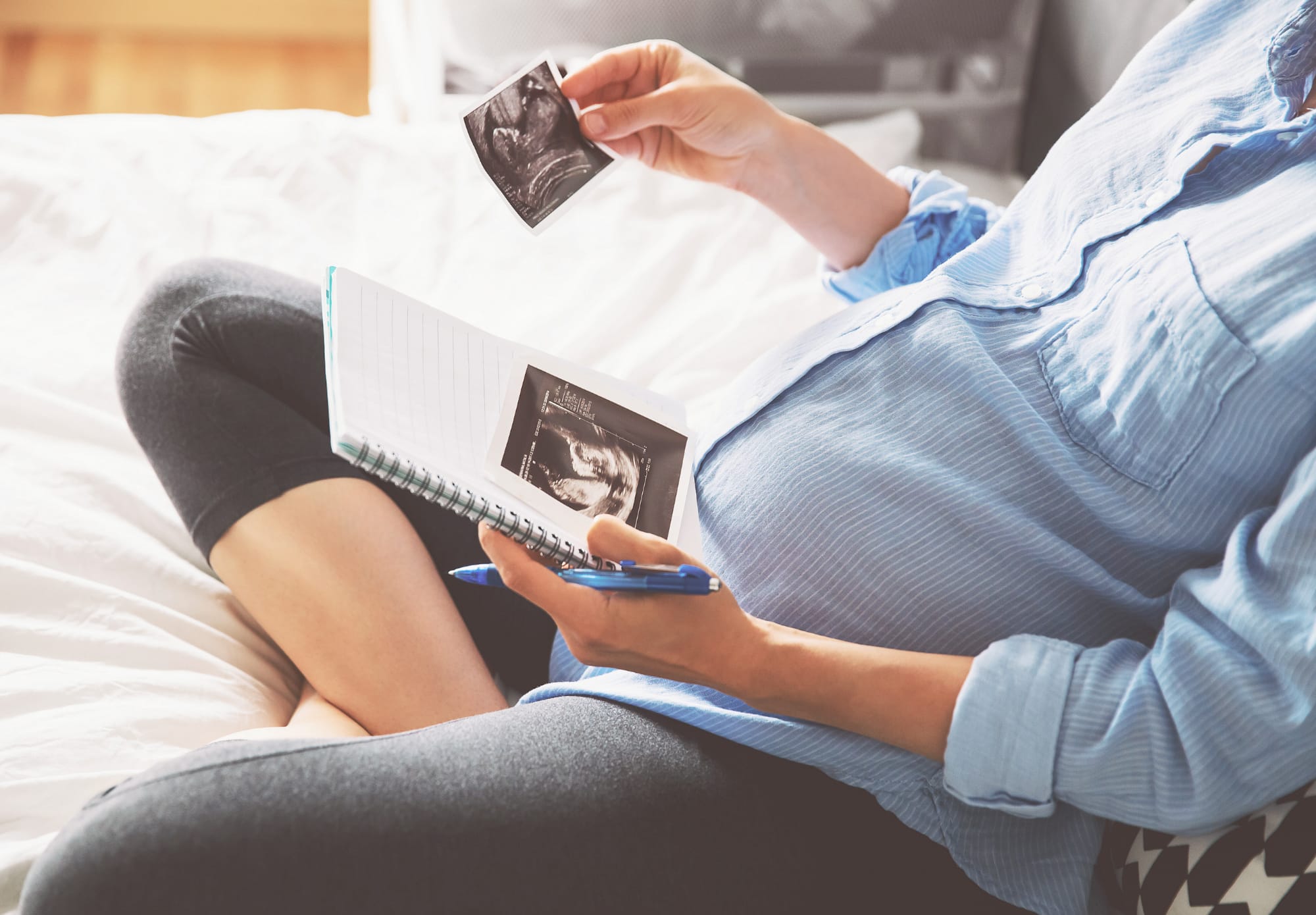 pregnant woman looking at sonograph photos with a notebook