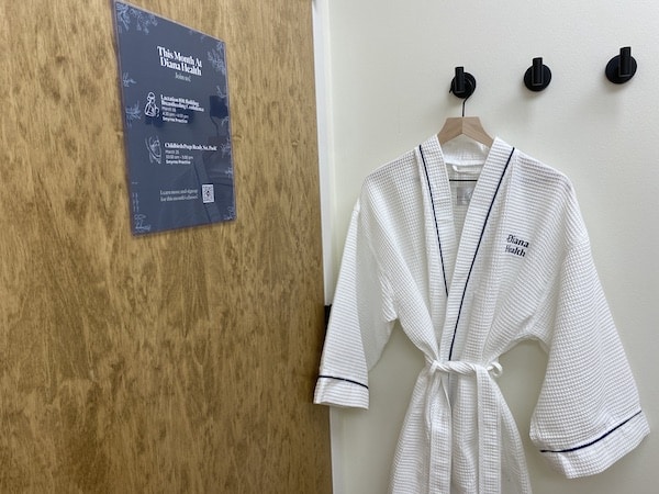 Photo of a Diana Health exam room with a white, branded Diana Health robe hanging next to the door