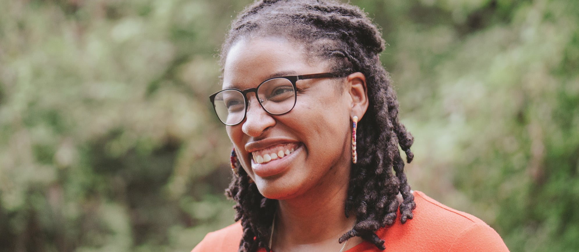Black woman with glasses in a park smiling